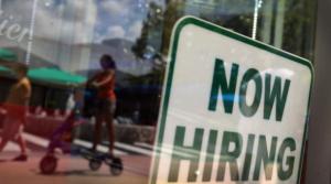 A ''Now Hiring'' sign is seen in the store front window in Miami, Fla.